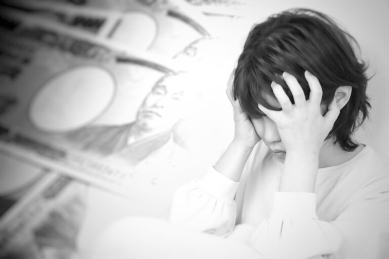 お金のことで頭を抱えて悩む女性