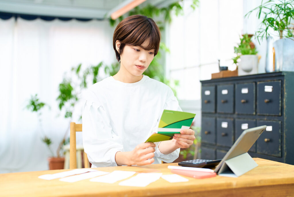 通帳を見て考える若い女性