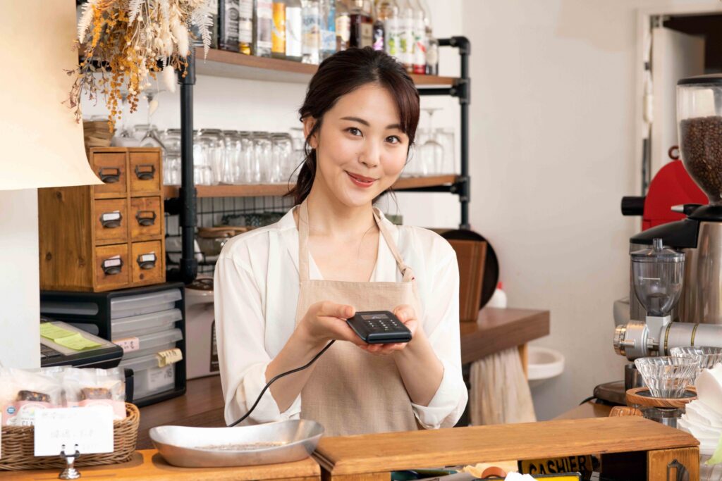 キャッシュレス決済端末を手に持っている女性