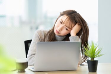パソコン画面を見て首をかしげる女性