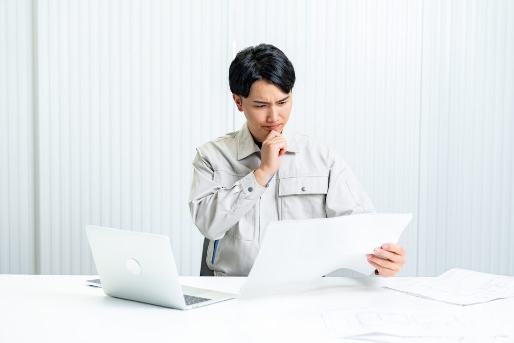 書類を読む作業着の男性