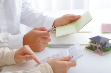 夫婦が通帳と電卓をもって借り換えローンの話し合いをしている