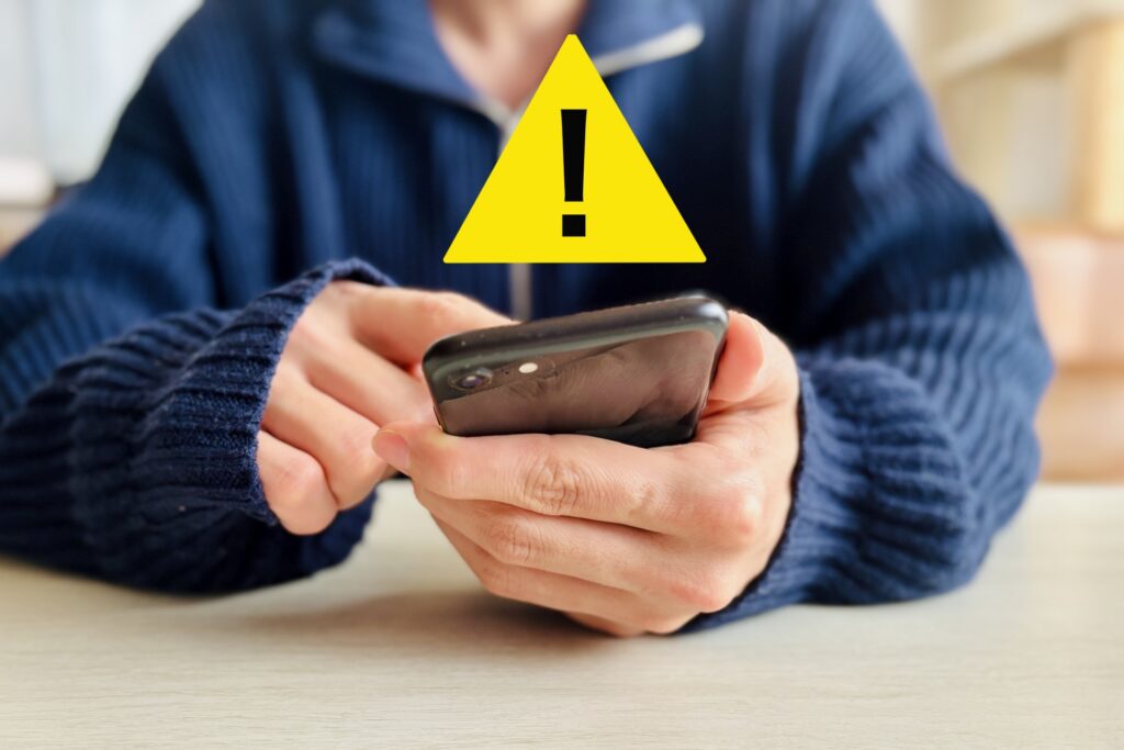 スマホを手に持つ人の前に!マーク