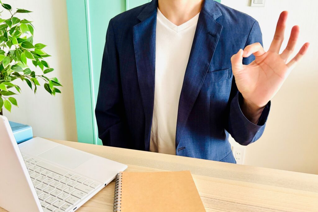 パソコンの前でOKサインを出している人