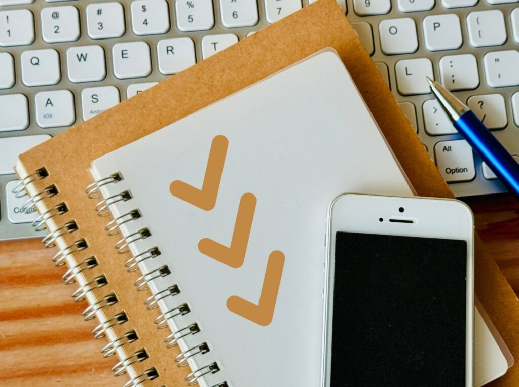 ノートに3つのチェックマークとスマホが置かれている