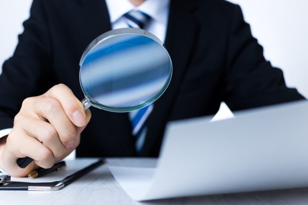 書類をルーペで見ているカード会社の社員のイメージ画像